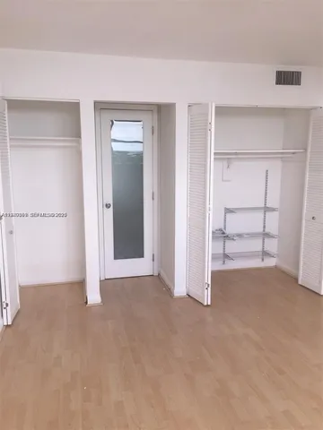 a view of an empty room with closet and a window