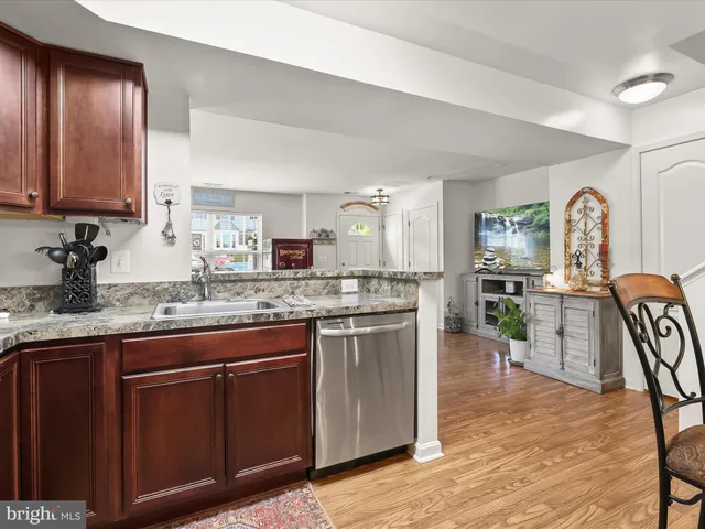 a kitchen with stainless steel appliances granite countertop wooden cabinets a sink a stove a dining table and chairs