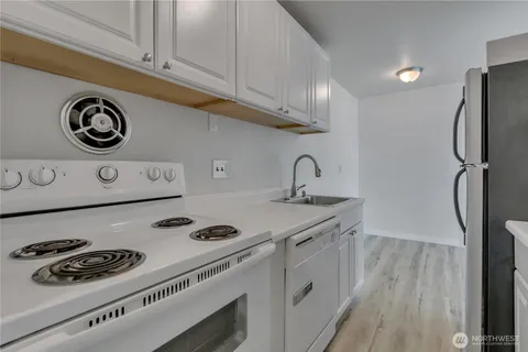 a kitchen with a refrigerator a stove and wooden floor