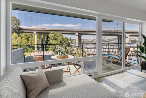 a living room with furniture a floor to ceiling window and dining table