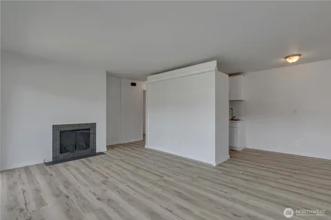 a view of an empty room with wooden floor and a fireplace