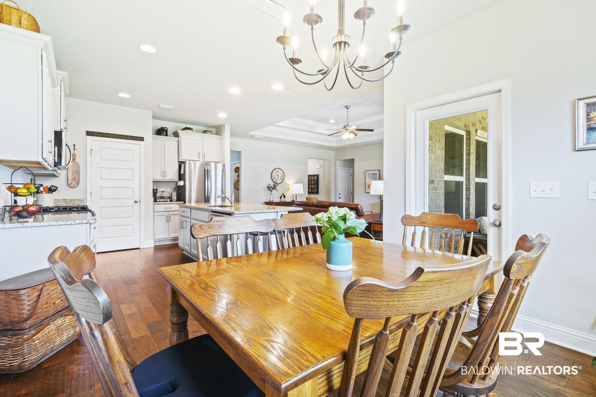 31663 Kestrel Loop Daphne, AL 36527 - Photo 31 of 86 Dining area featuring ceiling fan with notable chandelier, dark wood-type flooring, and a tray ceiling