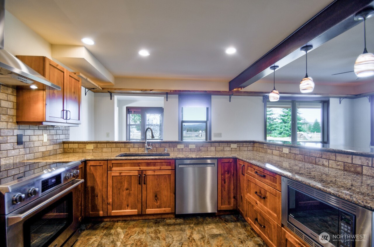 7737 Bordeaux Vista Road Southwest Olympia, WA 98512 - Photo 4 of 38 a kitchen with stainless steel appliances granite countertop a stove a sink and a microwave