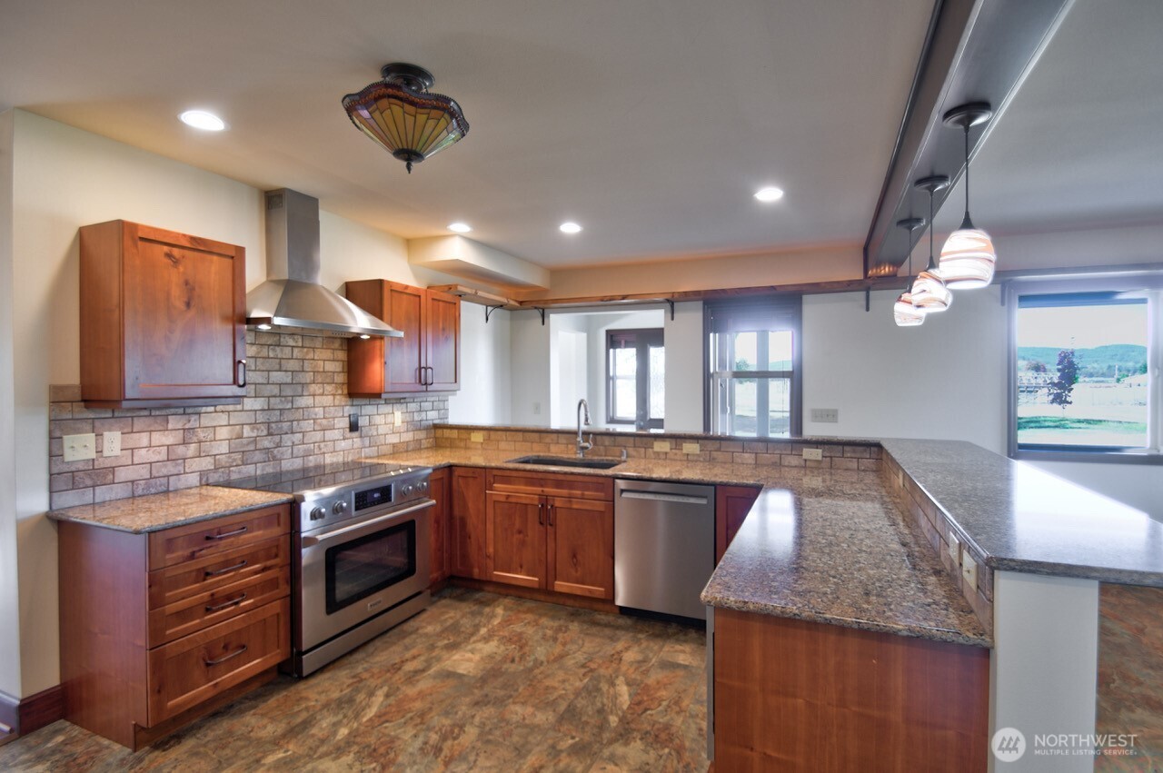 7737 Bordeaux Vista Road Southwest Olympia, WA 98512 - Photo 5 of 38 a large kitchen with stainless steel appliances granite countertop a sink counter space cabinets and a large window