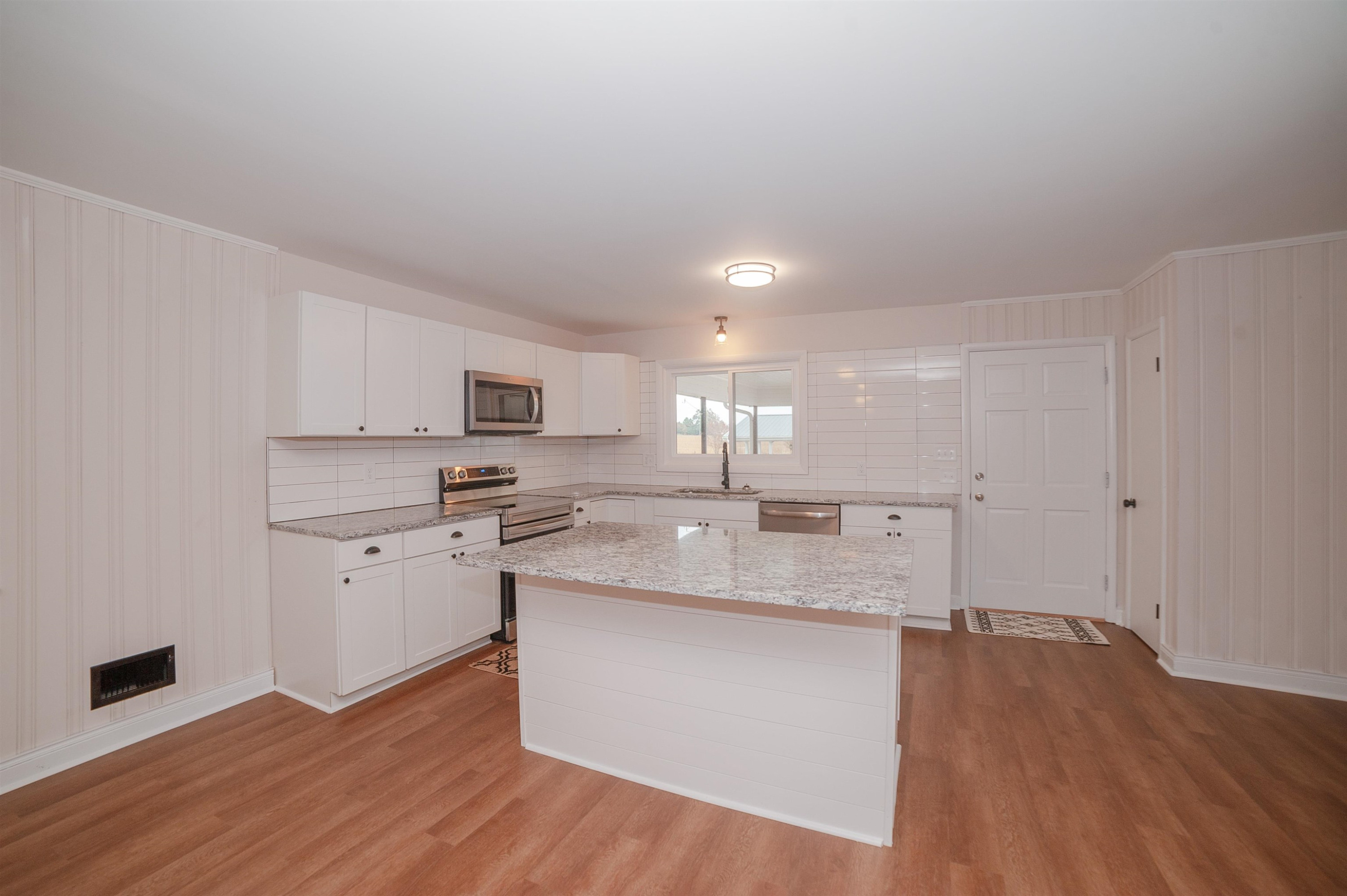 1206 Erwin Road Dunn, NC 28334 - Photo 7 of 24 a kitchen with stainless steel appliances granite countertop a sink a stove a refrigerator and white cabinets with wooden floor