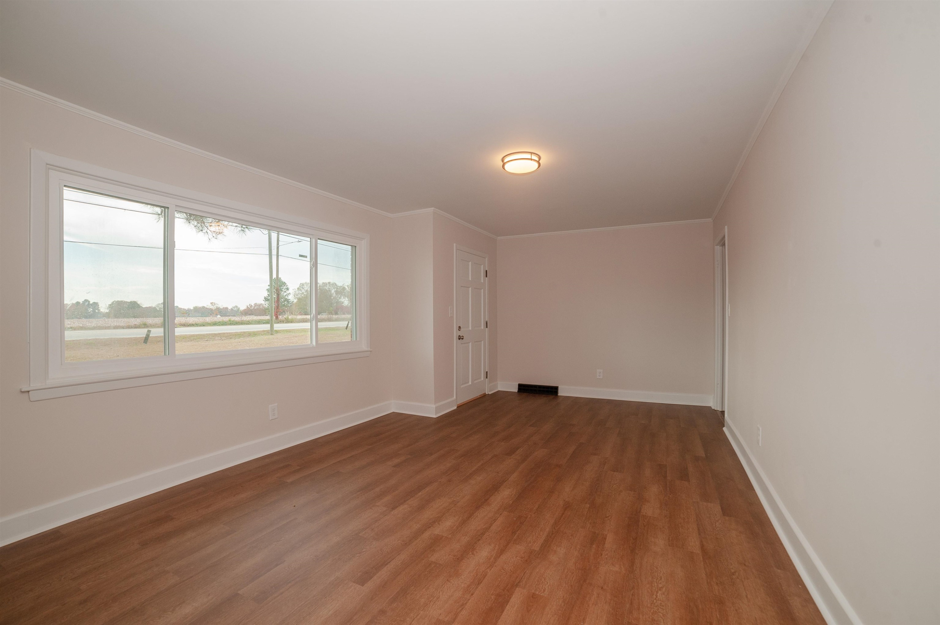 1206 Erwin Road Dunn, NC 28334 - Photo 10 of 24 an empty room with wooden floor and windows