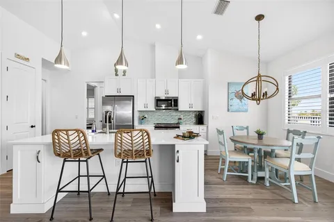a kitchen with stainless steel appliances kitchen island granite countertop a stove a sink a dining table and chairs with wooden floor