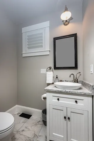 a bathroom with a granite countertop toilet sink and mirror
