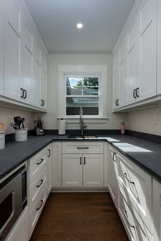 a kitchen with stainless steel appliances granite countertop a sink dishwasher a stove and white cabinets with wooden floor