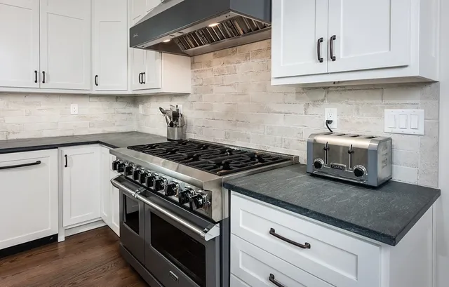 a kitchen with granite countertop white cabinets and stainless steel appliances