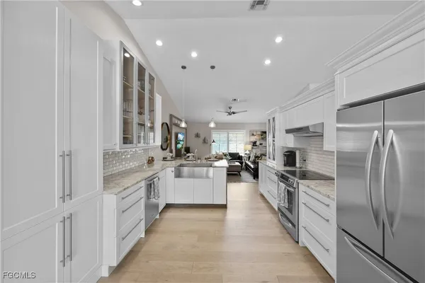 a large kitchen with stainless steel appliances lots of white cabinets