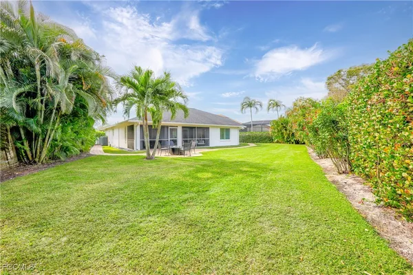 a view of a house with a big yard plants and large trees