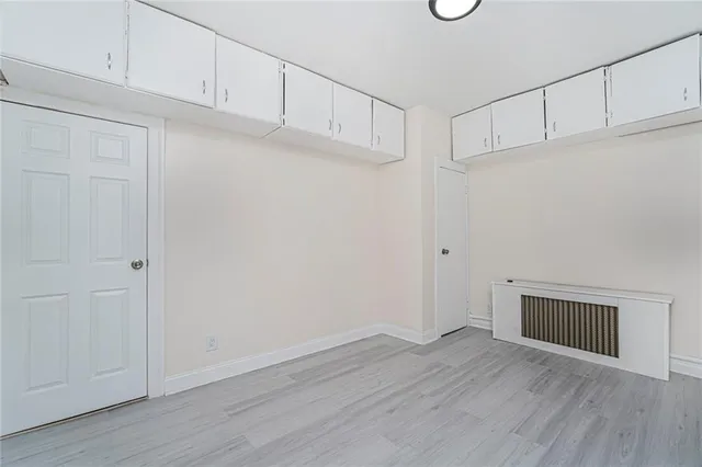 a view of an empty room with wooden floor and cabinets