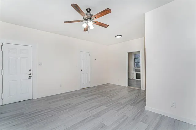 an empty room with wooden floor and a ceiling fan