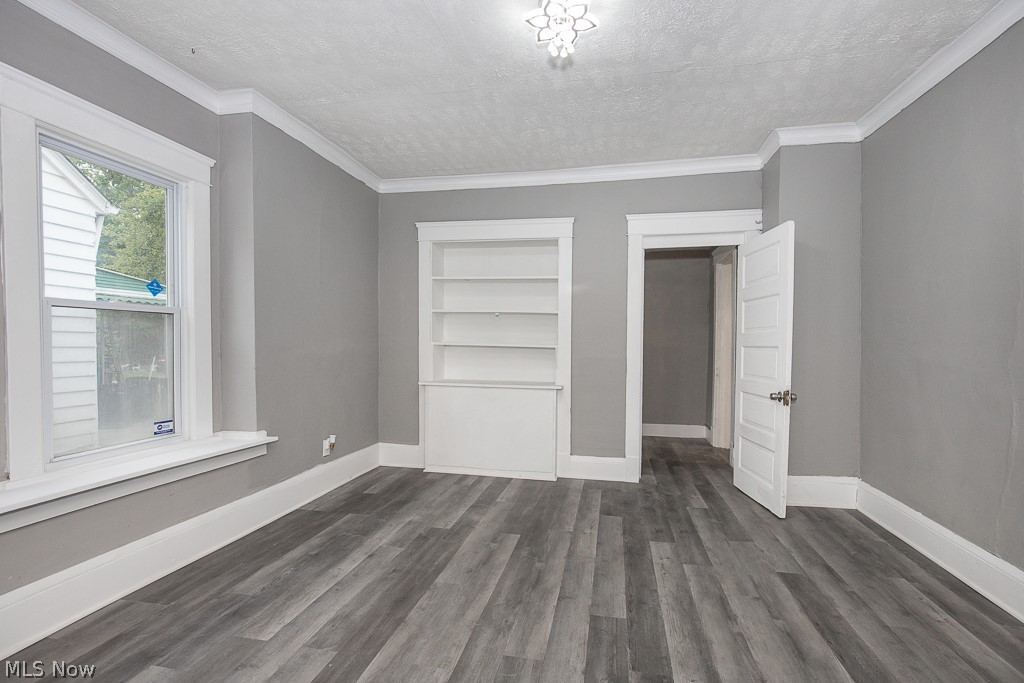 1892 Beersford Road Cleveland, OH 44112 - Photo 9 of 47 Unfurnished bedroom with dark hardwood / wood-style floors, ornamental molding, and a textured ceiling