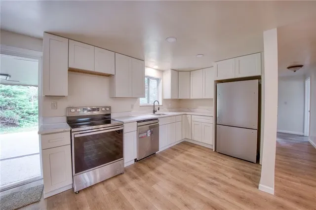 a kitchen with a refrigerator stove and wooden floor
