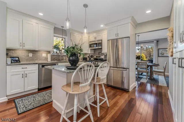 a kitchen with stainless steel appliances a dining table chairs refrigerator and sink
