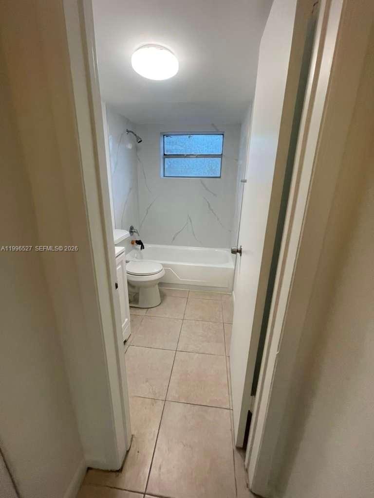 7101 Southwest 89th Court, Unit 102 Miami, FL 33173 - Photo 2 of 7 a bathroom with a sink a toilet a mirror and a shower