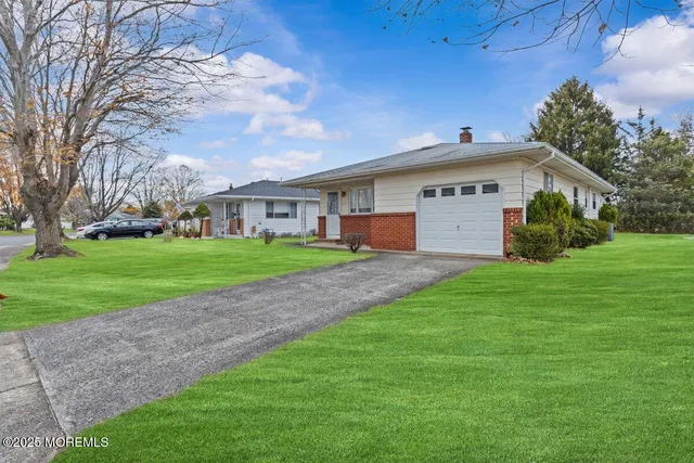 a view of a white house with a big yard and large trees