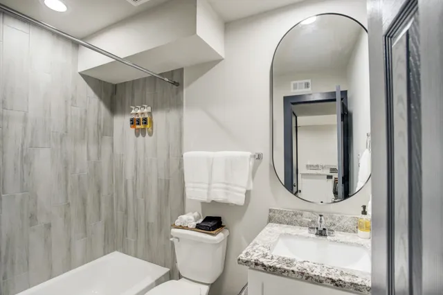 a bathroom with a granite countertop sink mirror vanity and toilet