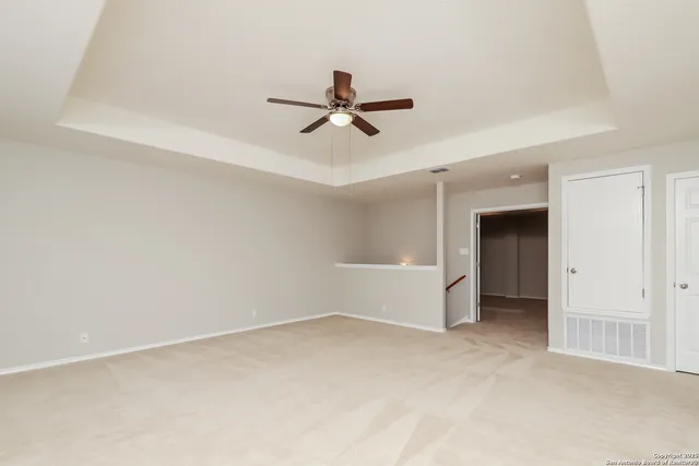 an empty room with chandelier fan and windows