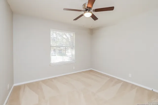 an empty room with a window and a fan