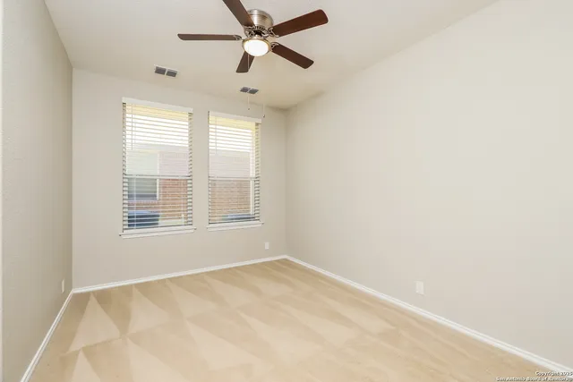 an empty room with windows and fan