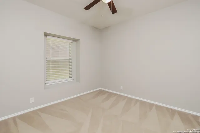 an empty room with a window and a ceiling fan