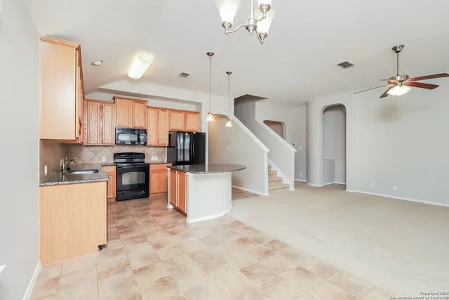 a kitchen with stainless steel appliances a refrigerator a stove top oven a sink dishwasher a dining table and chairs with wooden floor