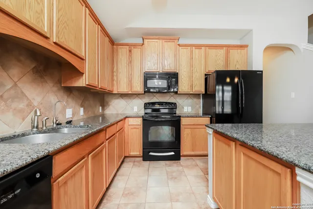 a kitchen with granite countertop a refrigerator stove and sink