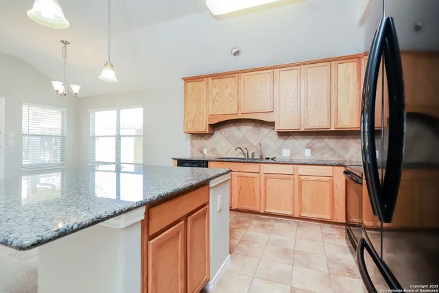 a kitchen with granite countertop a sink a counter space appliances and cabinets