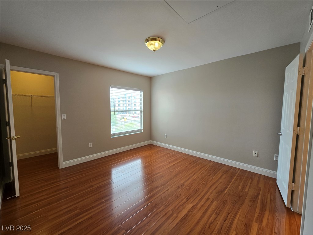 8000 West Badura Avenue, Unit 2135 Las Vegas, NV 89113 - Photo 15 of 28 Unfurnished bedroom featuring a walk in closet and wood finished floors