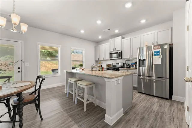 a kitchen with white cabinets stainless steel appliances and wooden floor