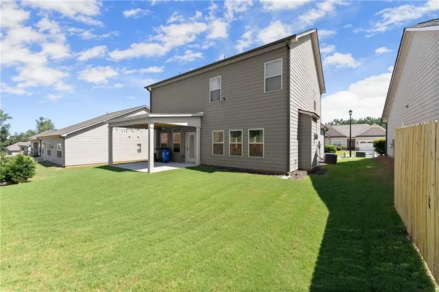 a view of a house with a yard and large tree