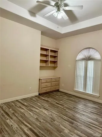 an empty room with wooden floor fan and windows
