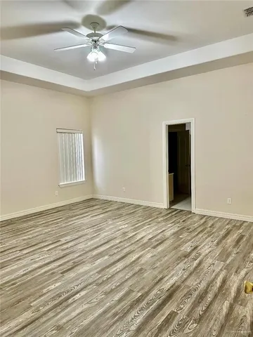 a view of an empty room with window and a chandelier fan