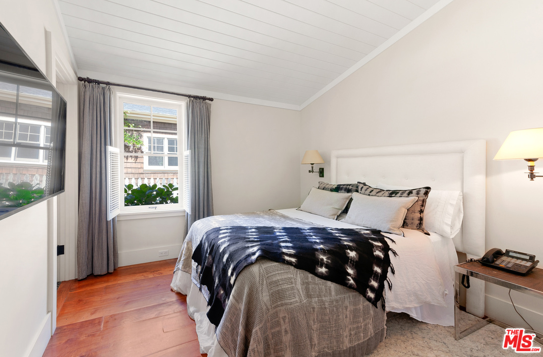 6763 Zumirez Drive Malibu, CA 90265 - Photo 21 of 52 a bedroom with a bed and wooden floor