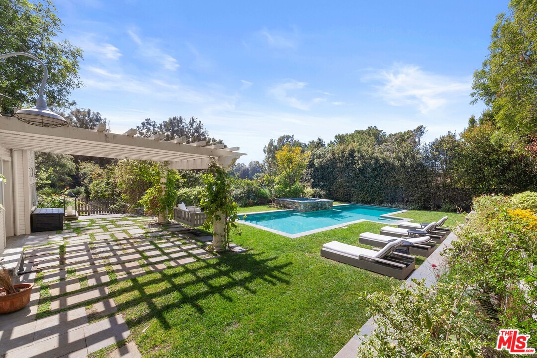 6763 Zumirez Drive Malibu, CA 90265 - Photo 34 of 52 a view of a swimming pool with lawn chairs and a big yard