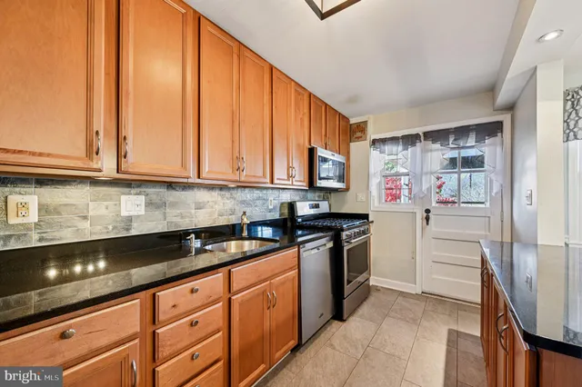a kitchen with granite countertop a sink cabinets and stainless steel appliances