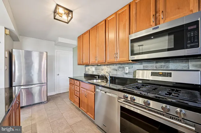 a kitchen with stainless steel appliances granite countertop a stove a refrigerator and a microwave