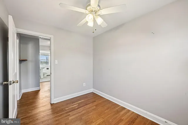 an empty room with wooden floor and fan