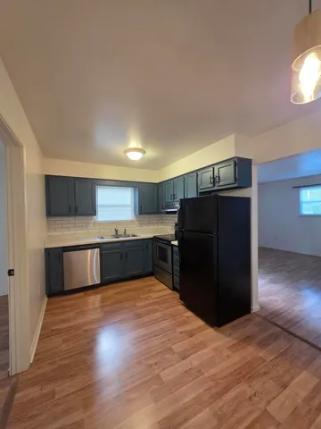 a kitchen with stainless steel appliances granite countertop a refrigerator and a wooden floors