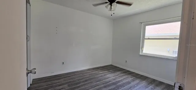 an empty room with a window and a ceiling fan