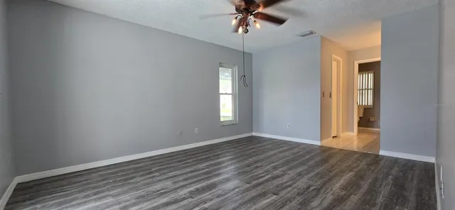 a view of an empty room with a window and wooden floor