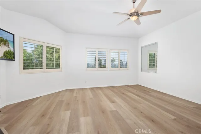a view of empty room with wooden floor and fan