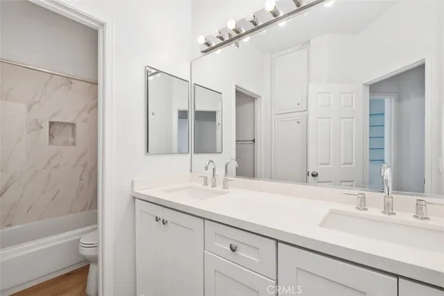 a bathroom with a double vanity sink a toilet and shower