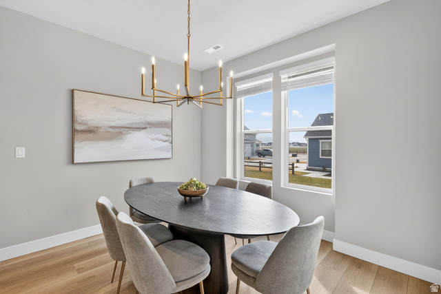 2841 West 2705 North, Unit 69 Ogden, UT 84404 - Photo 5 of 31 Spacious dining area featuring light wood-finish flooring, a contemporary brass chandelier, a large picture window, and neutral wall tones