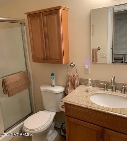 a bathroom with a granite countertop toilet sink and mirror