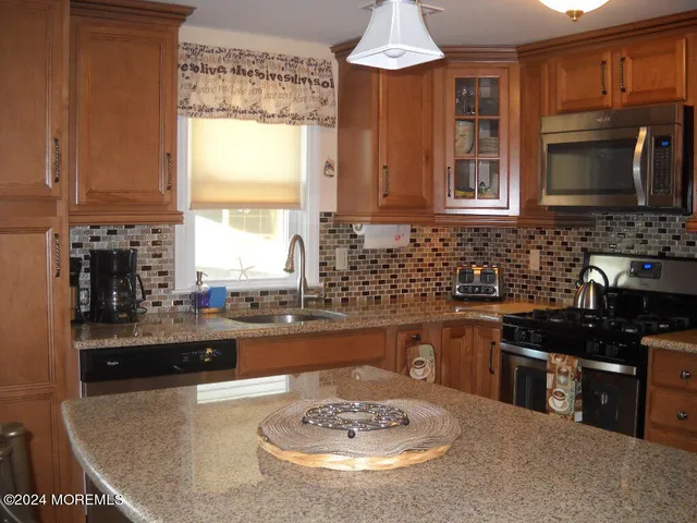 a kitchen with granite countertop a stove a sink a counter space and cabinets