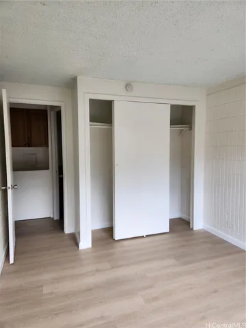 a view of an empty room with wooden floor and closet